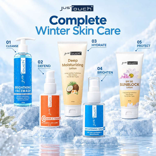 JustTouch Complete Winter Skin Care set displayed on ice blocks with a snowy, icy background. The set includes five products: a blue Brightening Facewash, an orange Clean C Serum, a beige Deep Moisturizing Lotion, a blue Brightening Serum, and a yellow SPF 80 Sunblock Lotion.